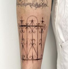 a person with a tattoo on their leg that has an iron gate in the middle