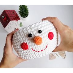 a person holding up a crocheted snowman ornament