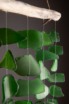 a green glass wind chime hanging from a wooden stick