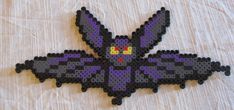 a piece of art made out of perler beads on a white sheet with the image of a bat