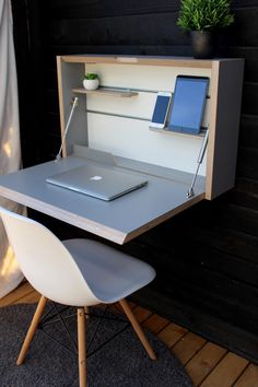 an open laptop computer sitting on top of a wooden desk next to a white chair