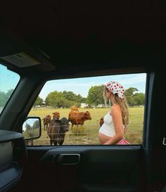 a pregnant woman in the back seat of a car looking at cows