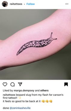 a tattoo on the arm of a woman with a black and white image of a slug