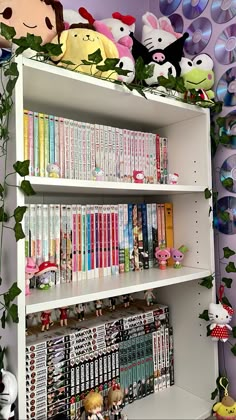 a book shelf filled with lots of books next to a wall covered in cartoon characters