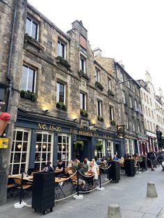 people sitting at tables in front of an old building