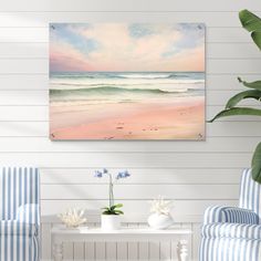 a living room with two blue chairs and a painting on the wall above it that has a beach scene in pastel colors