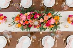 the table is set with white plates and pink napkins, gold place settings, and colorful flowers