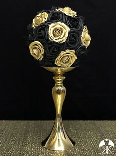 a gold vase with black roses on it