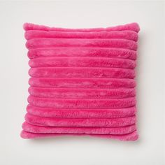 a pink pillow that is on top of a white wall