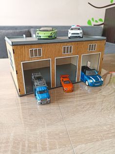 three toy cars are parked in front of a house with two garages on the floor