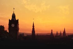 the sun is setting over an old city with steeples and spires in silhouette