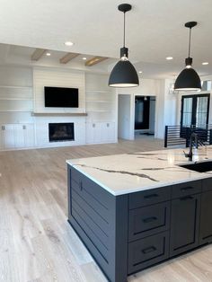 a large kitchen with an island in the middle and two pendant lights hanging from the ceiling