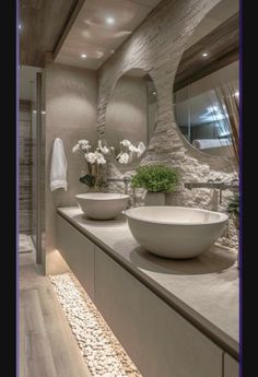 two white bowls sitting on top of a counter in front of a mirror and sink