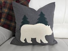 a white bear pillow sitting on top of a couch next to a plaid throw pillow