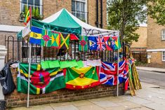 an outdoor market with flags hanging from it's sides on the sidewalk in front of a brick building