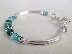 This bracelet has been uniquely created by combining emerald and light turquoise crystals together. Such a pretty combination! Perfect for your upcoming wedding to gift to your bridesmaids, mother of bride/groom, Jr bridesmaids, etc. OR, a great birthday, anniversary or just because gift. Choose from a toggle or lobster claw clasp from the dropdown menu at checkout. ~ 6mm and 4mm emerald and lt turquoise swarovski crystals ~ sterling silver bead caps ~ silver plated curbed tube bead bangles and Stackable Jewelry For May Birthstone Gift, Stackable May Birthstone Jewelry As Gift, Stackable May Birthstone Jewelry Gift, Sterling Silver Bracelets For May Birthstone Anniversary, Adjustable Turquoise Jewelry For May Birthstone, Green Birthstone Bracelets For Anniversary, Elegant Stackable Jewelry For Birthday, Green Birthstone Bracelet For Anniversary, Elegant Turquoise Birthstone Bracelets