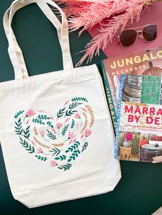 a tote bag, book and sunglasses are on the table next to some books