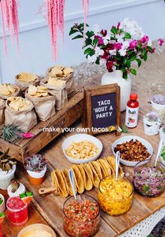 a table filled with lots of food on top of a wooden tray next to flowers