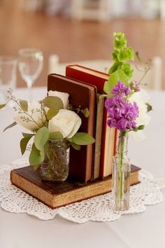 two books are sitting on a table with flowers in vases next to each other