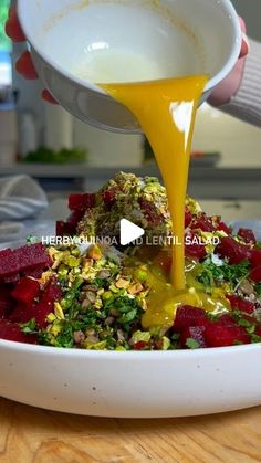 someone pouring dressing onto a salad in a bowl