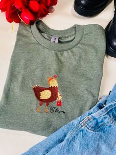 a Chic-n embroidered design on a Hanes Eco Smart/ Bella Canvas/ Gildan Crewneck Tee ( T- Shirt) Gifts For Chicken Lovers, Chicken Lovers, Embroidered Crewneck, Hoodie Size Chart, Couple Halloween, Colour Star, Embroidered Shirt, Embroidered Design, Kids Sweatshirt