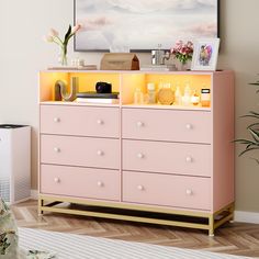 a pink dresser with yellow drawers and pictures on top