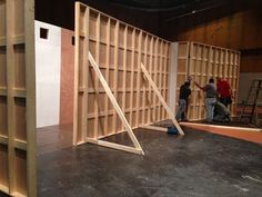 three men are working on the walls of a room that is being constructed with plywood