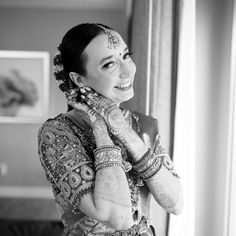 a woman with henna on her face and hands in front of a window smiling at the camera