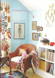 a living room with blue walls and colorful rugs on the hardwood floor, white shelving unit