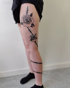 a woman's legs with barbed wire and flowers on them