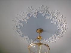 a white and gold chandelier hanging from the ceiling in a room with lace doily