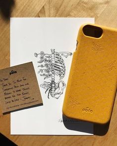 a yellow phone case sitting on top of a piece of paper next to a note