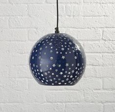 a blue and white hanging light with stars on the ceiling next to a brick wall