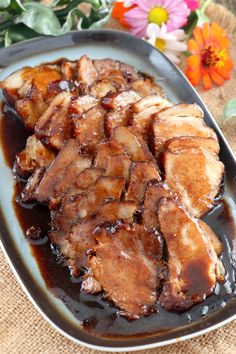 pork chops covered in bbq sauce on a plate next to flowers and napkin