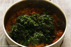 spinach and carrots cooking in a pot on a wooden table