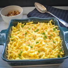 a blue casserole dish filled with pasta and vegetables