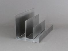 three pieces of metal sitting on top of each other in front of a gray background