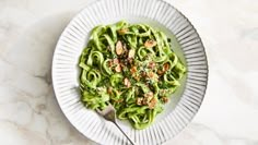 a white plate topped with pasta covered in pesto