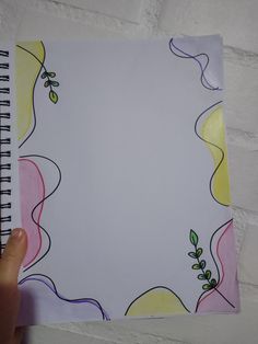 a hand holding up a spiral notebook with flowers on it