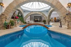 an indoor swimming pool in a house with stone arches on the ceiling and blue water