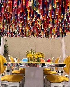 an outdoor dining area with yellow chairs and colorful paper streamers hanging from the ceiling