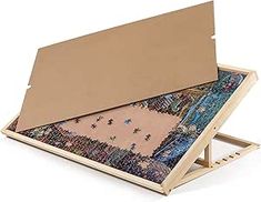 an open cardboard box filled with different colored fabric and wooden tray holding a piece of art work