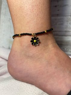 Black Beaded Anklet with Gold Accents and Black Flower Charm Length: 10" - 11 1/2" Black Flower Shaped Beaded Bracelets For Gift, Black Flower Shaped Beaded Bracelets, Black Flower Beaded Bracelets For Gift, Black Beaded Festival Anklets, Black Beaded Anklets For Festival, Handmade Black Flower Bracelets, Black Bohemian Anklets With Black Beads, Adjustable Black Flower Jewelry, Black Bohemian Beaded Anklets