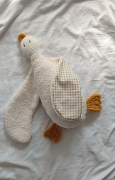 a stuffed animal laying on top of a white sheet