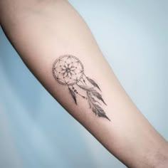 a woman's arm with a tattoo on it that has a small dream catcher