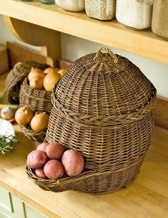 some potatoes are sitting in a basket on a counter next to other vegetables and jars