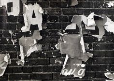 black and white photograph of torn up letters on a brick wall