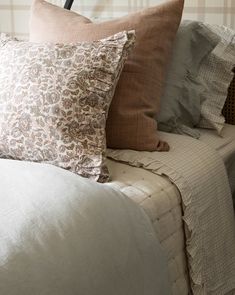 a bed topped with lots of pillows on top of it's headboard next to a wall