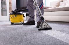 a man is cleaning the floor with a mop and vacuum cleaner in front of him