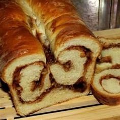 a loaf of cinnamon roll sitting on top of a wooden cutting board